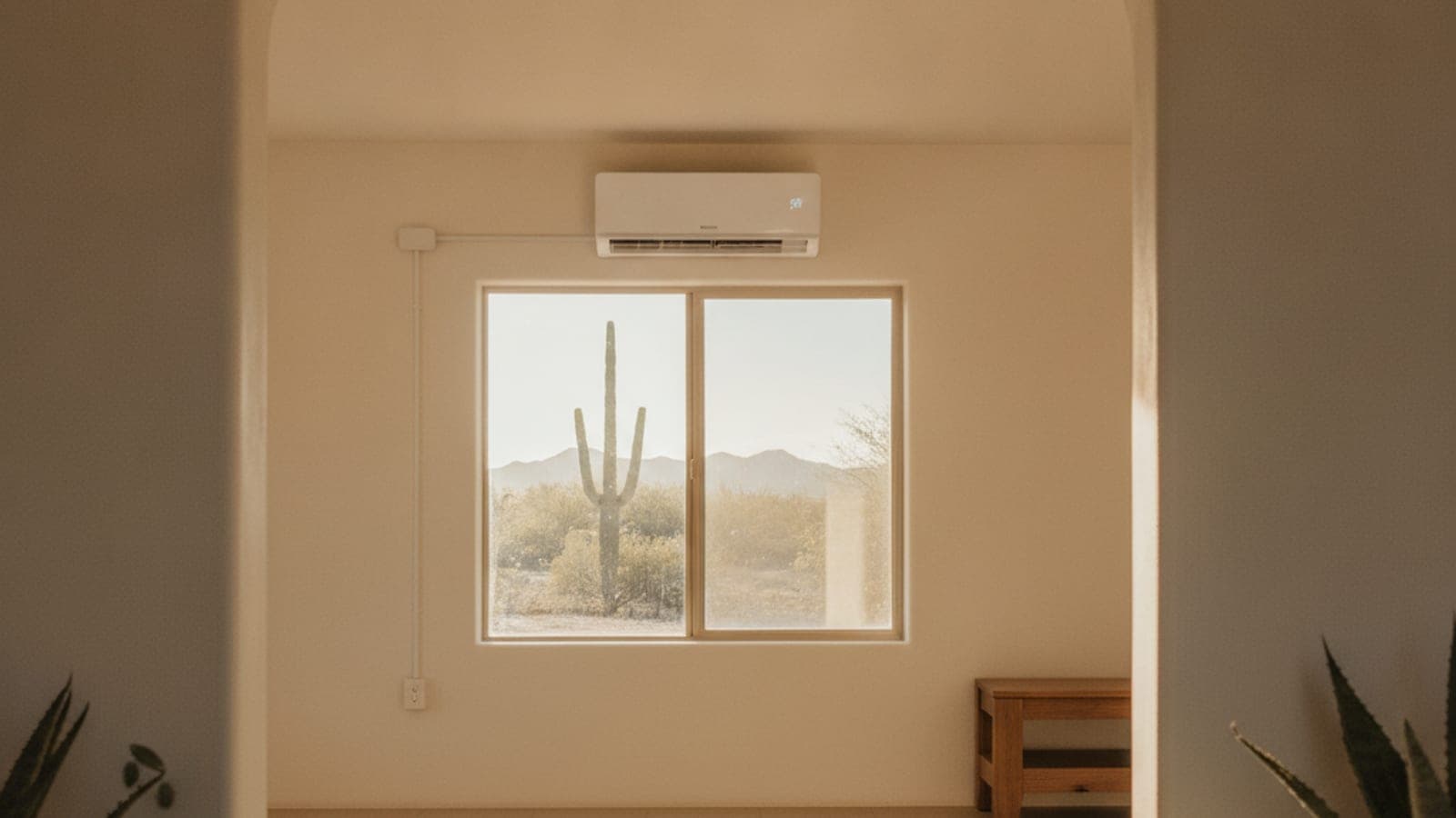 Sala amplia y luminosa en Tucson con un minisplit de pared sobre una ventana y techo plano, con un saguaro visible afuera en luz cálida