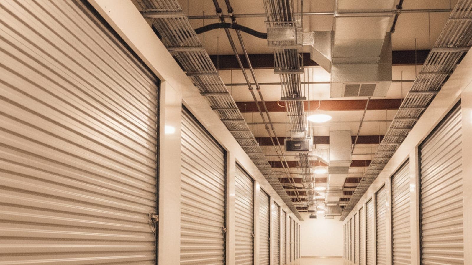 Pasillo interior de un edificio de almacenamiento con clima controlado, con puertas enrollables, ductos en el techo y sin personas