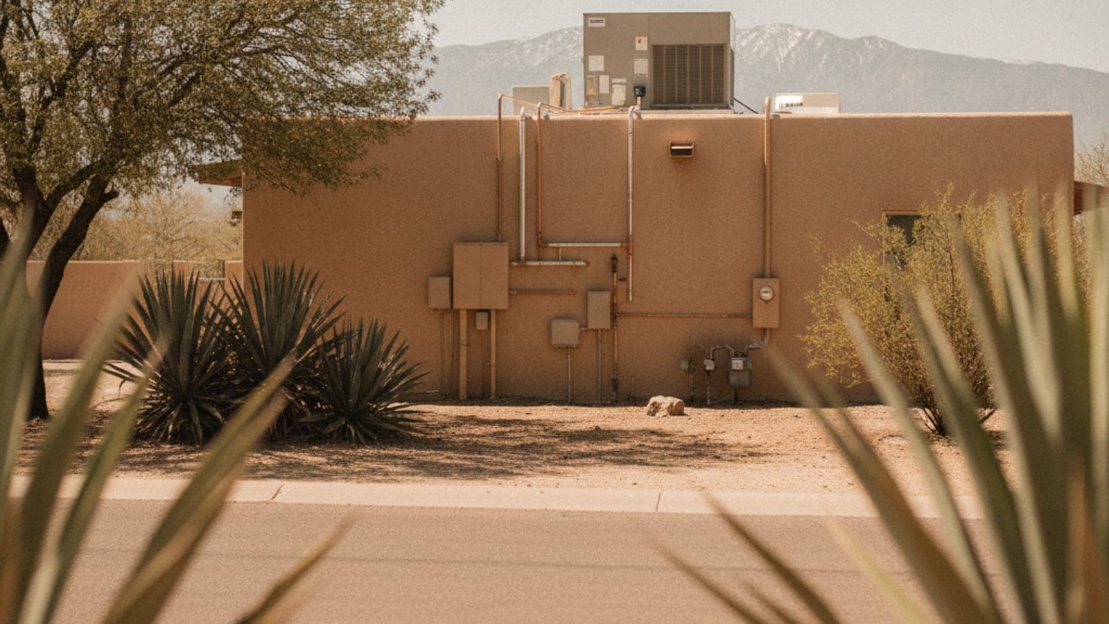 Dueño de casa en la puerta de entrada de una casa de estuco en Tucson mirando un termostato en un día caliente
